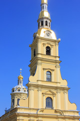 Fototapeta na wymiar Peter and Paul Cathedral at Peter and Paul Fortress in Saint Petersburg, Russia. Bell Tower of Christian Church, Religious Building Architecture Details. Church Tower View on Clear Blue Sky Background