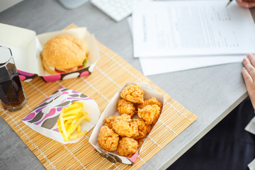 Chicken nuggets with burger and french potatoes on the desk with business papers