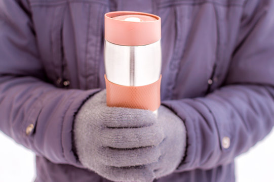 thermos in the hands of a man close-up against the snow