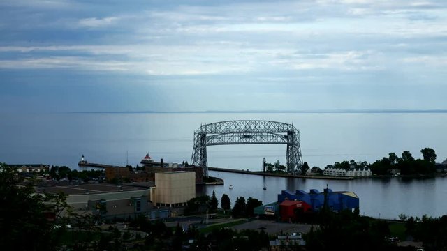 Time lapse of iron ore ship going under the historic aerial lift bridge in Duluth, Minnesota under cloudy skies, leaving Lake Superior and entering Duluth Harbor.