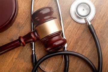 Gavel and stethoscope on wooden background, symbol