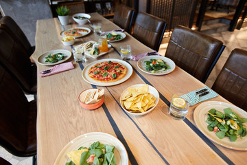 Various kinds of fresh food on plates, drinks in glasses and snacks in bowls served for clients of cafe