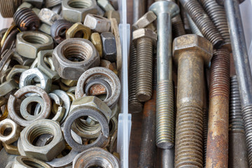 Rusty used nuts and bolts in opened storage box closeup