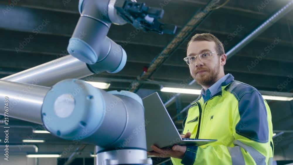 Aufkleber low angle shot at the factory: automation engineer uses laptop for programming robotic arm. new era 