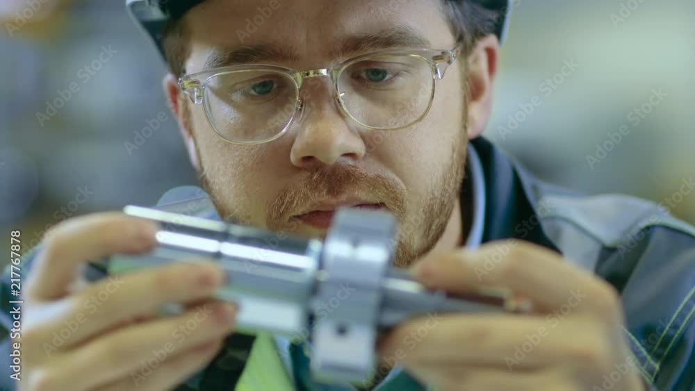 Fototapete close-up shot of the industrial engineer wearing classes and hard hat connects two components he des