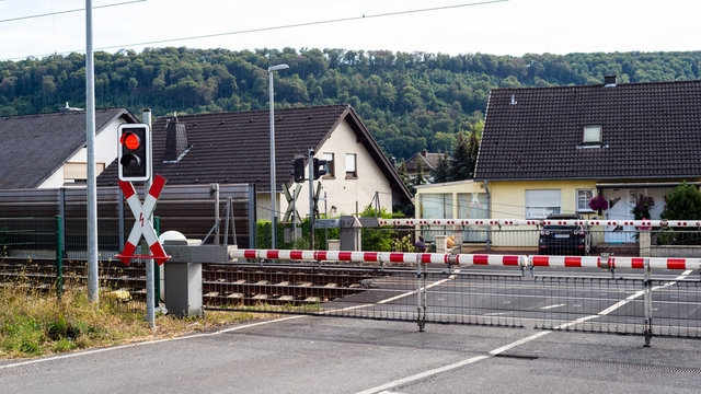 A guarded railway crossing with closed barriers and a red light.