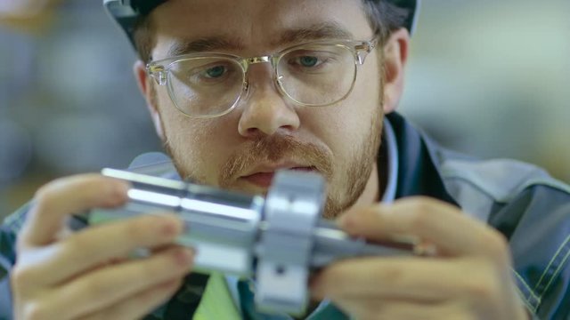 Close-up Shot of the Industrial Engineer Wearing Classes and Hard Hat Connects Two Components He Designed. Precision in Mechanical Engineering.
