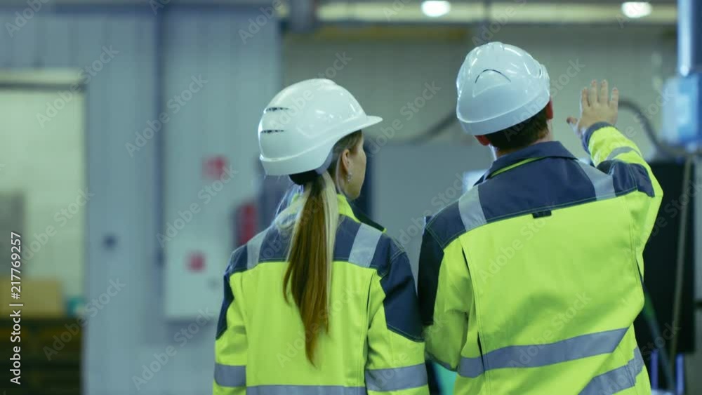 Aufkleber male industrial worker and female chief mechanical engineer in walk through manufacturing plant whil
