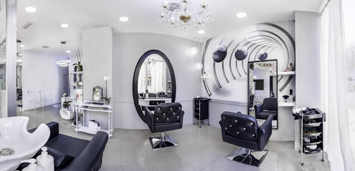 Fototapeta na wymiar Panorama of a modern bright beauty salon. Hair salon interior business with black and white luxury decor.