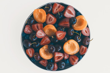 Top view of cake covered with fresh cherries, strawberry, and apricot isolated on white background