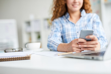 Young agent with smartphone texting or searching for contact of client to arrange appointment