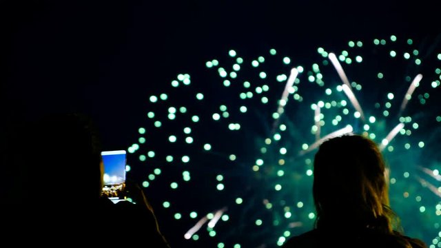 People shoot fireworks on the phone and watch the salute through the smartphone screen