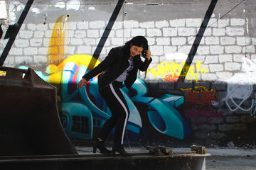 Model balancing over metal bar in front of graffiti