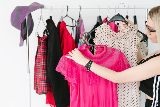 personal style consultant or fashion stylist choosing trendy clothing for her client. woman holding two tops on hangers.