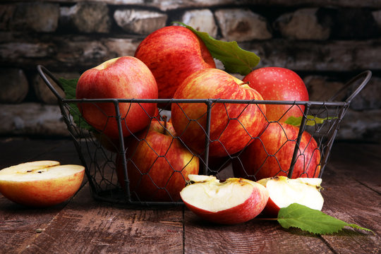 Ripe red apples with leaves on wooden background