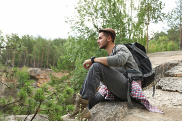 Young man on rocky mountain near forest. Camping season