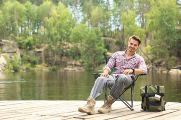 Fototapeta premium Young man resting on wooden pier near lake. Camping season