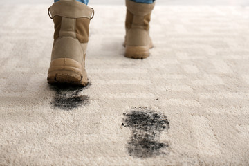 Person in dirty shoes leaving muddy footprints on carpet