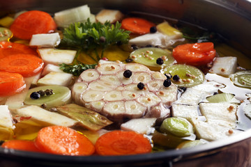 Fototapeta na wymiar Broth with carrots, onions various fresh vegetables in a pot - colorful fresh clear spring soup. Rural kitchen scenery vegetarian bouillon or stock