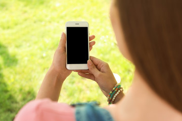 Woman using smartphone with blank screen outdoors, closeup. Mock up for design
