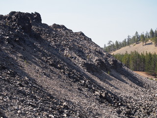 Textured Obsidian and hardened lava rock on a sunny fall day at the Big Obsidian Flow in the...