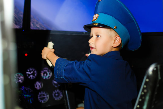 A happy, kindergarten boy toting in an oversized airline pilot uniform