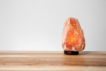 Himalayan salt lamp on table against light background