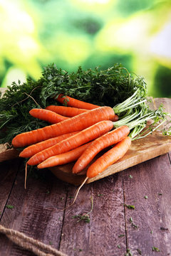 Fresh organic carrots with green leaves on wooden background. Ve