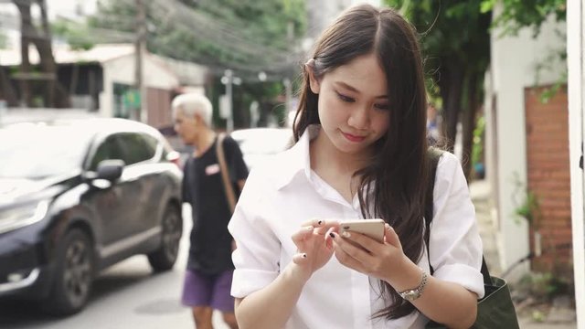 Young asian woman using mobile smartphone at street side, urban woman lifestyle
