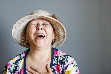 An elderly lady in a hat laughs from the heart