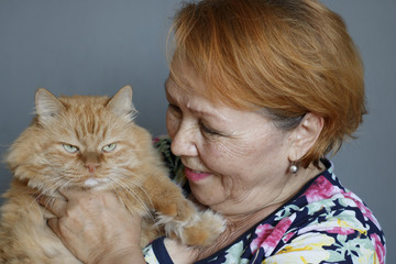 Portrait of an elderly lady with her big favorite ginger cat