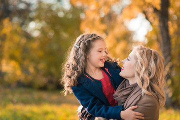 Happy joyful woman having fun with her girl in autumn color