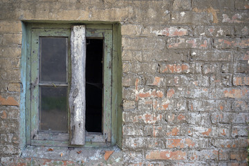 A broken window in an old abandoned brick building.