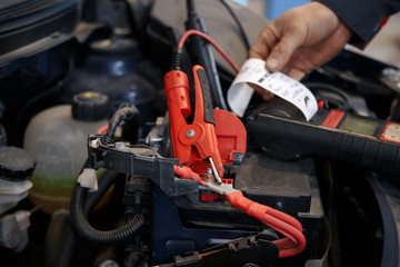 Mechanic using booster cables to start-up a car engine