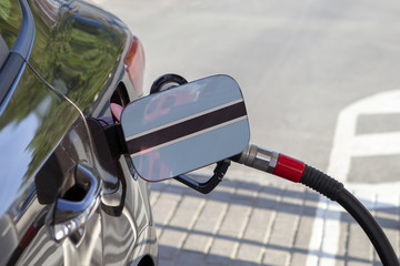 Fueling car with petrol pump at a gas station.