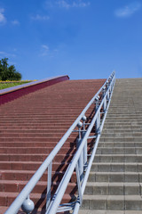 The red and gray stairs, with large steps, go up. Desktop background.