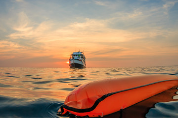 A surface marker buoy and dive boat on the surface of a warm tropical ocean at sunset - obrazy, fototapety, plakaty