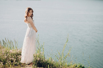beautiful boho girl standing near lake and relaxing. attractive young woman in white bohemian dress...