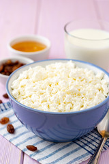 Cottage cheese in blue bowl on purple wooden background