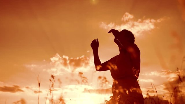 woman lifestyle praying on her knees. Girl folded her hands in prayer silhouette at sunset. slow motion video. Girl folded her hands in prayer pray to God. the girl praying asks forgiveness for sins