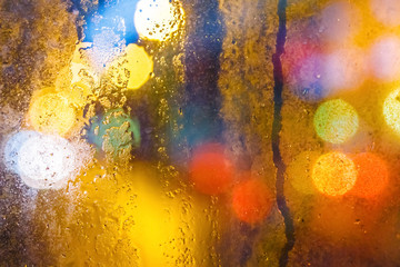 Rain drops on window with yellow glowing background