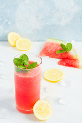 Fresh watermelon beverage in glass with lemon and mint with blue background