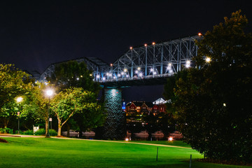 well lit bridge through a park at night with light bursts