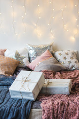 Xmas in morning bedroom. Double bed In christmas Interior on white wall background with cozy lights. Gift box on bed. Many pillows on bed