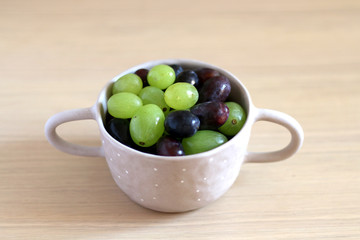Artisan ceramic bowl filled with various types of grapes. Selective focus.