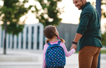 first day at school. father leads  little child school girl in first grade.