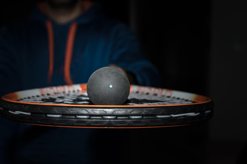 Single dot squash ball on the strings of a racquet