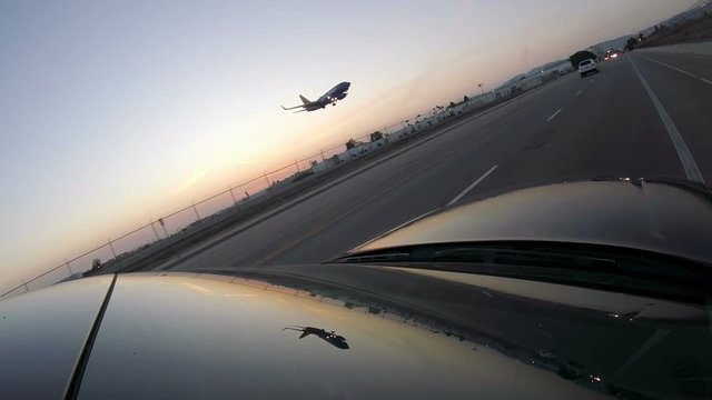 Airplane coming in for landing over driving car