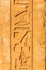 stone wall with Egyptian carving figures and hieroglyphs, Aswan, Egypt, Africa.