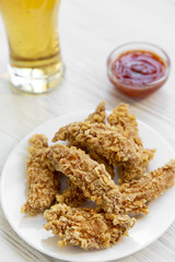 Fried chicken fingers with sauce and cold beer, side view. Closeup.